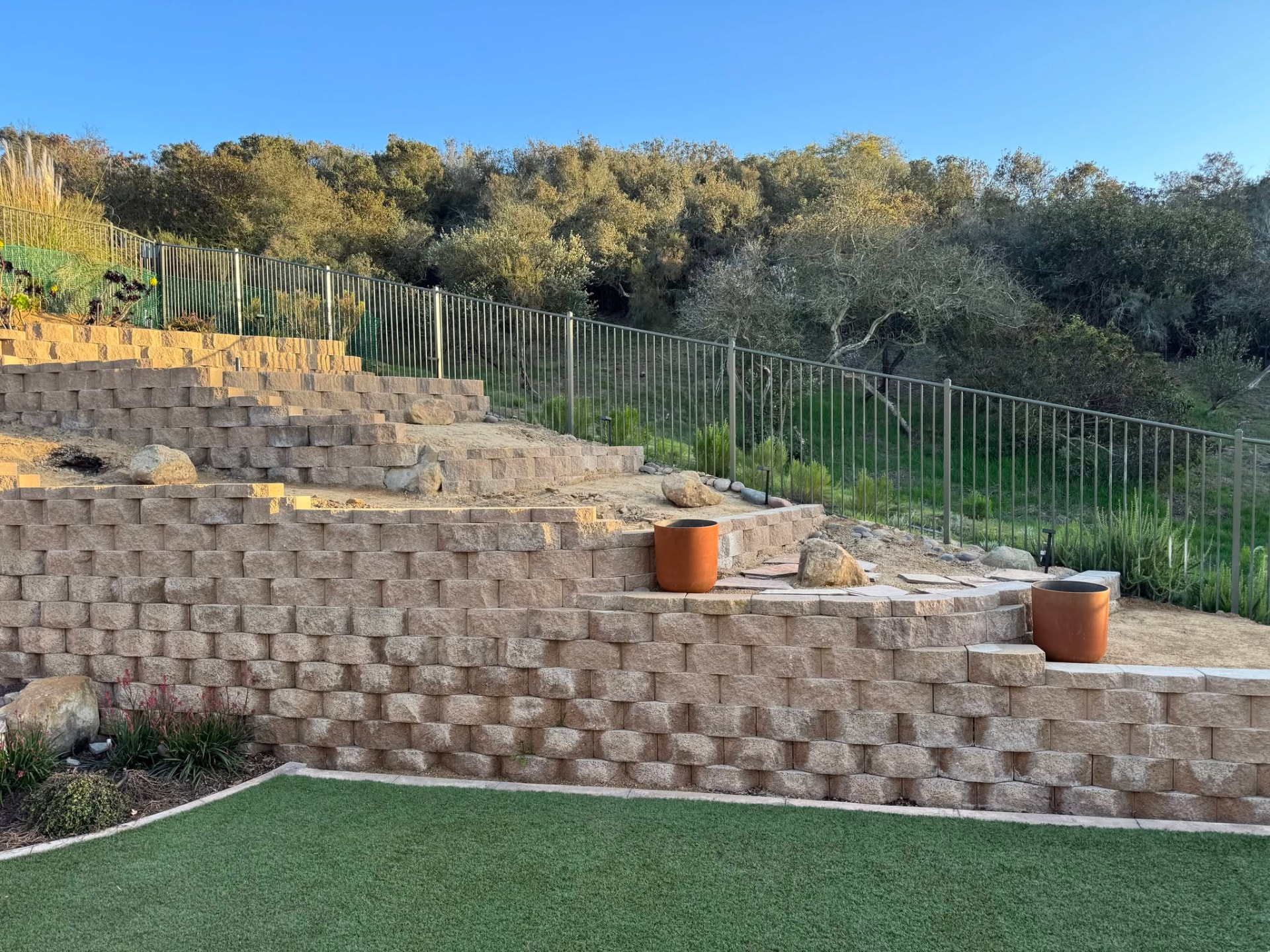 Completed stackable block retaining wall on a terraced residential hillside